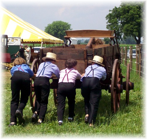 Amish boys pushing wood wagon at the Lancaster County Carriage & Antique Auction in Bird In Hand PA.