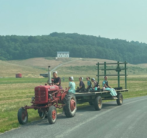 Amish girls on tractor and wagon